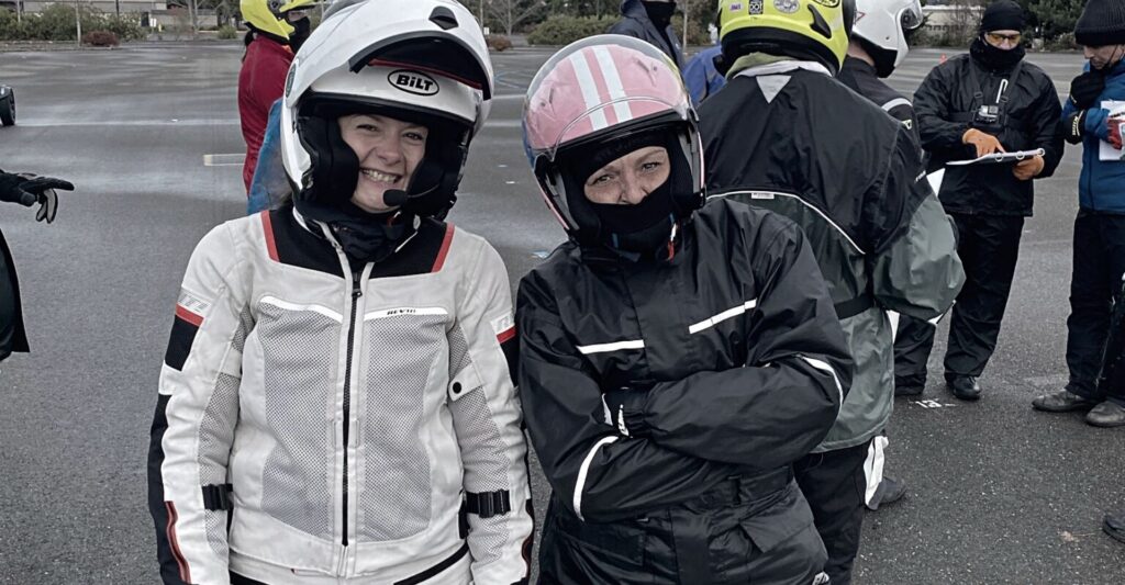 two female motorcycle students smiling while wearing their helmets