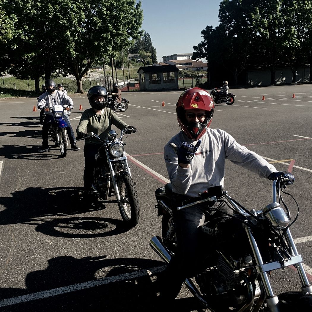 motorcycle students sitting on training motorcycles in a line smiling