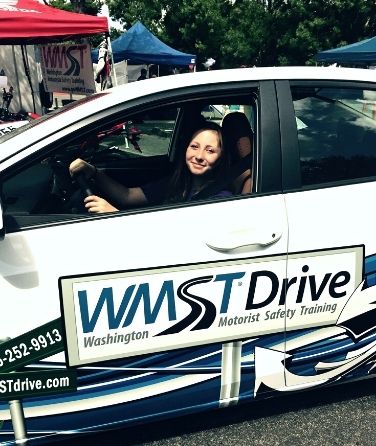 drivers education student siting in the driver seat and smiling